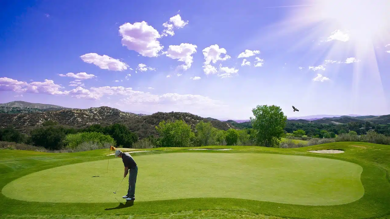 golfer chipping on the green with blue sky