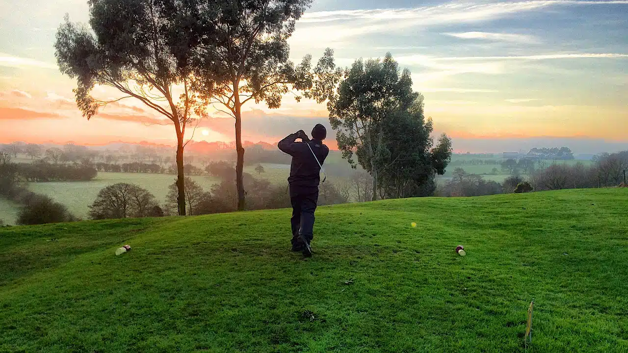 golfer hitting from rough on sunset