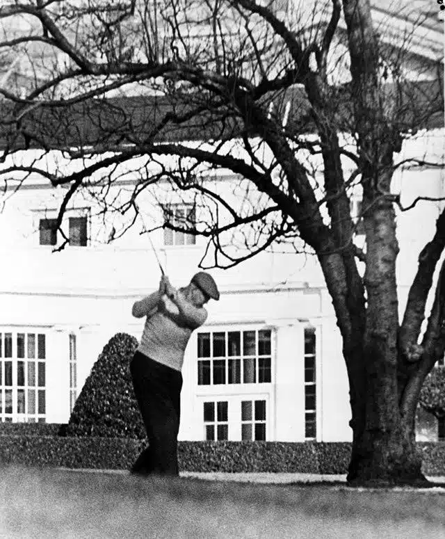 Dwight eisenhower swinging golf club in front of white house