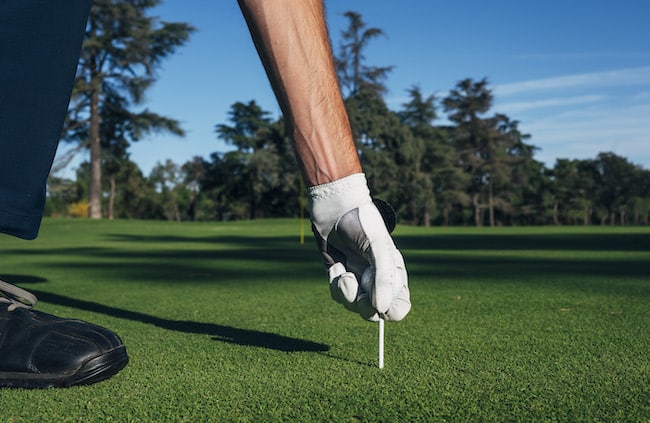 Golfer puts the golf ball on a tee