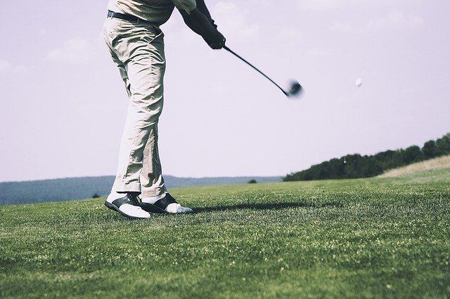 man hitting hybrid golf club