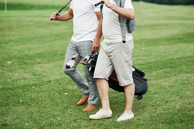 Cropped photo of two friends on the sports field with golf equipment