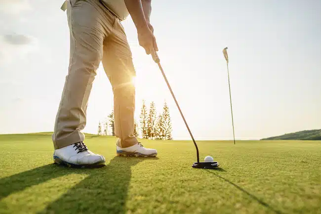 man putting on golf green about to hit