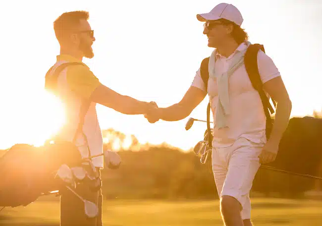 Handsome Men playing golf and shaking hands with sun setting