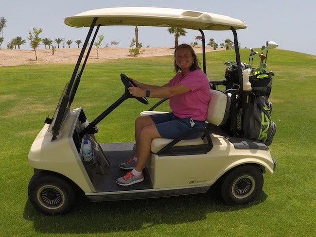 Should I Leave My Golf Cart Plugged In All The Time? lady in a golf cart on course