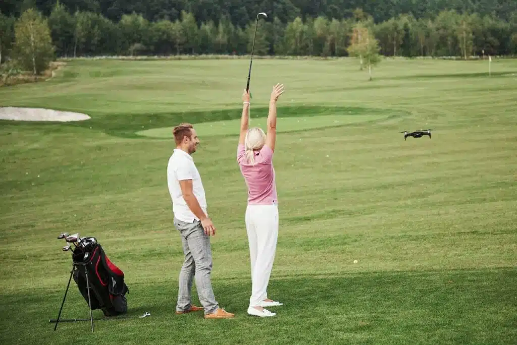 Group of stylish friends on the golf course learn to play a new game. Shooting is conducted from the quadrocopter drone