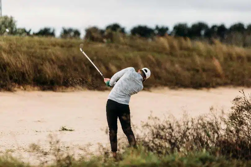 swinging golf club sand trap