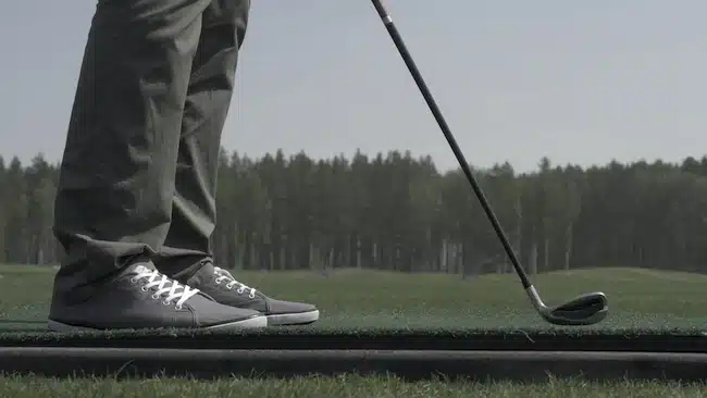 Golfer Hitting Ball with Club on Beautiful Golf Course. Golfer hits an fairway shot towards the club house. Man hitting driver on a golf course in the sun. Professional male golf player