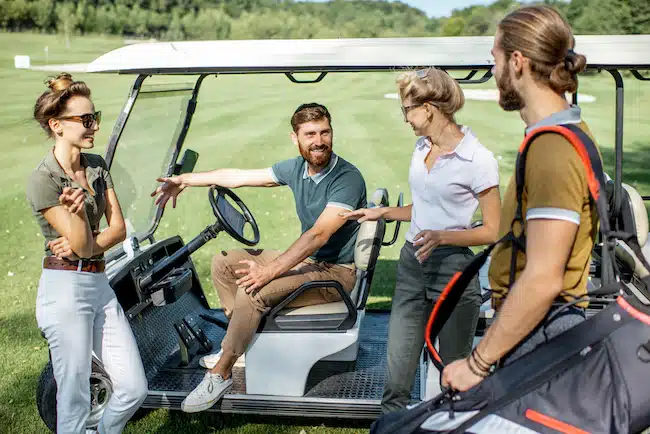 People laughing from golf puns near the golf car on the playing course