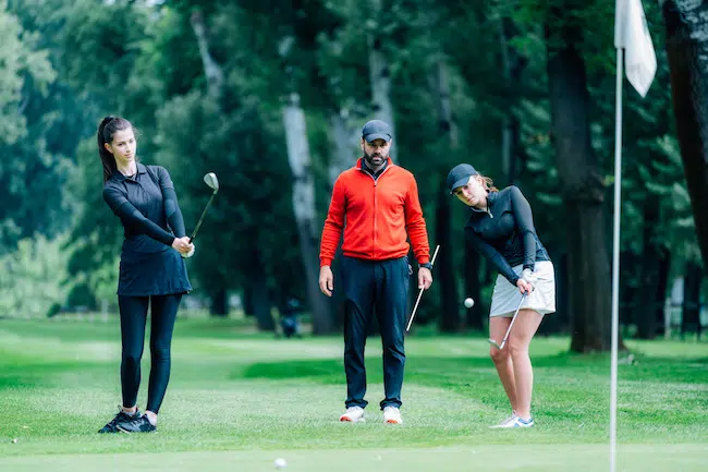 Two-young-golfers-practicing-chipping-shots-on-a-g-2021-08-28-23-18-32-utc