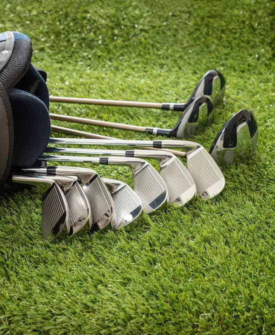 Golf clubs on green grass golf course, close up view.