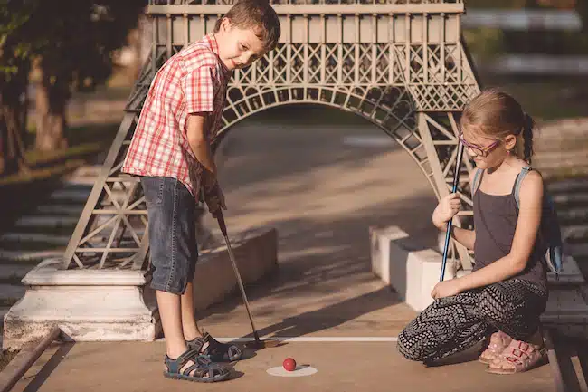 Happy brother and sister playing mini golf.