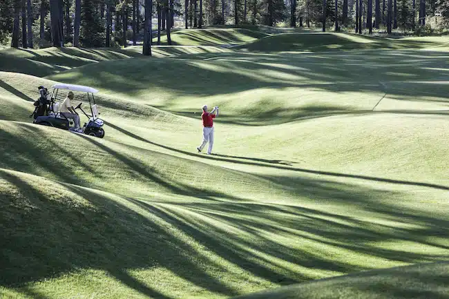 Senior golfer hitting a second shot from the fairway of a golf course.