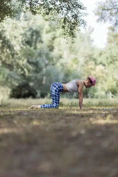 Young woman with pink hair doing yoga at park