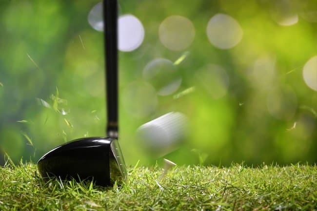 Golfer teeing off golf ball from tee on beatuiful golf course