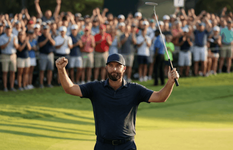 A pro golfer raising a putter in celebration on the final green