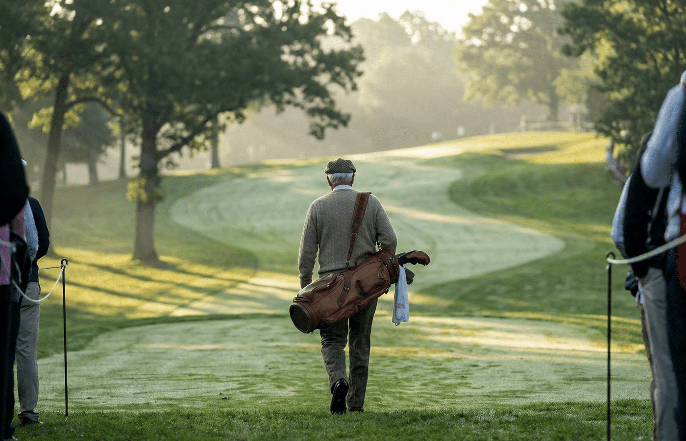 A legendary golfer walking a hilly fairway from behind.