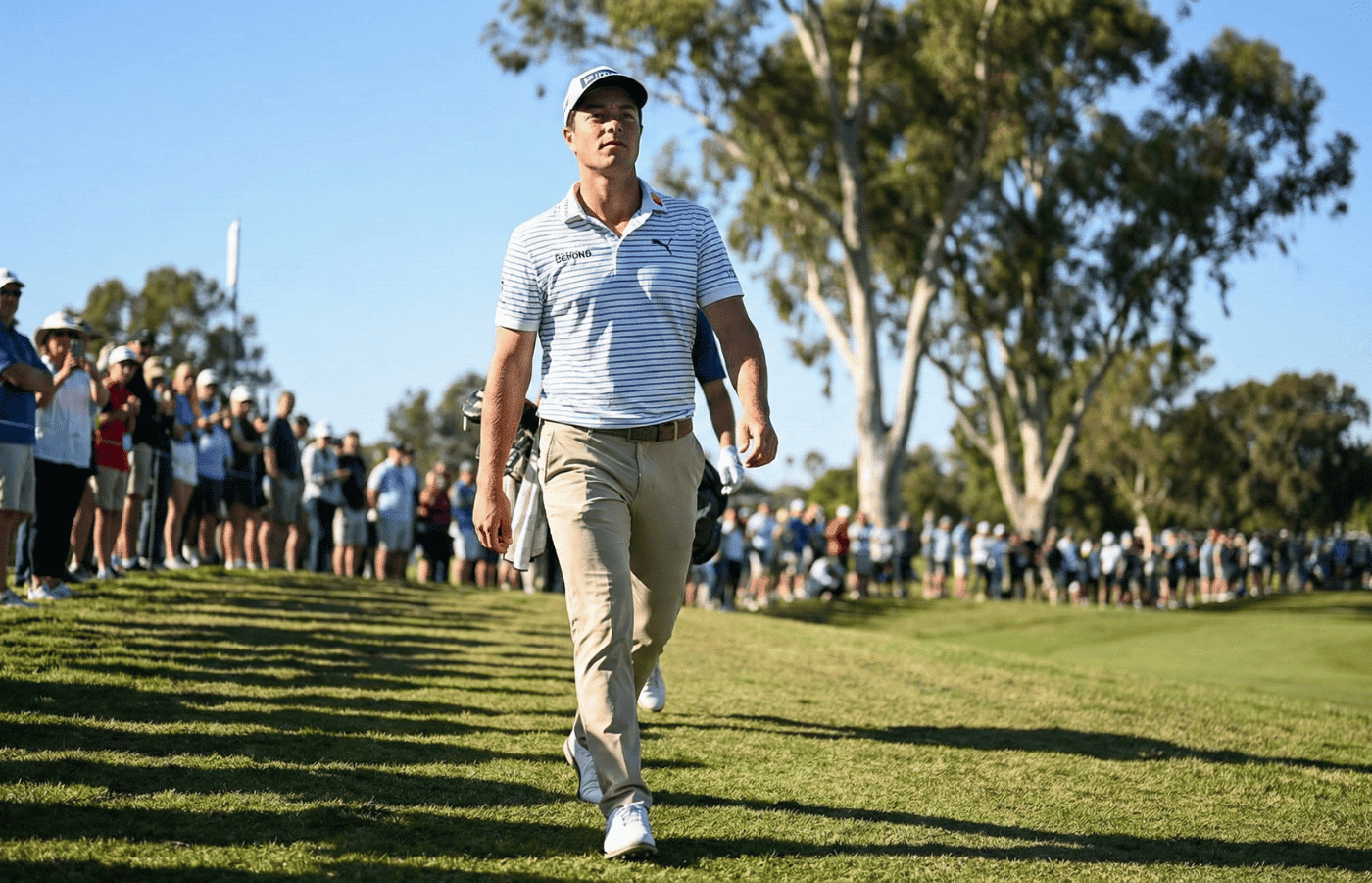 A pro golfer in a light-colored striped polo walking the Riviera Country Club