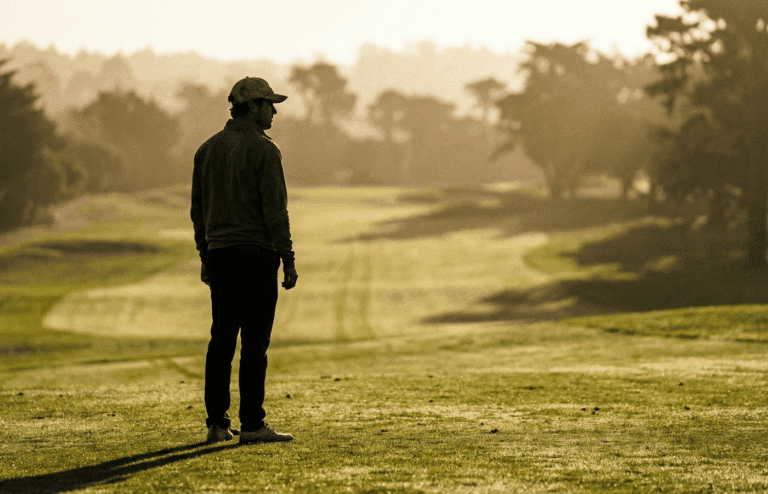 A golfer alone on a fairway at dusk.