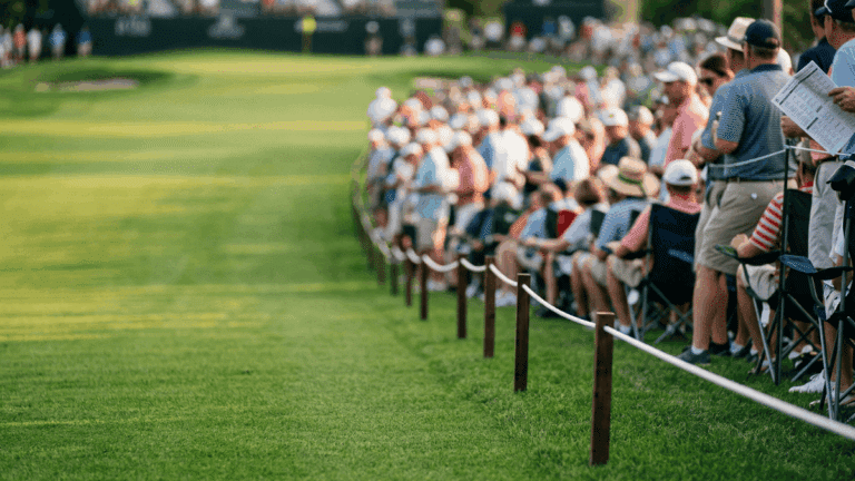The gallery ropes lining the side of a PGA course with audience on one side and fairway on the other.