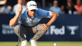 A golfer near the green, reviewing the path of his ball before a putt.